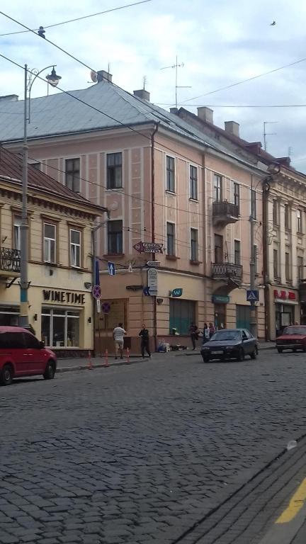 um grupo de edifícios numa rua com carros em Chernivtsi city center hostel em Chernivtsi