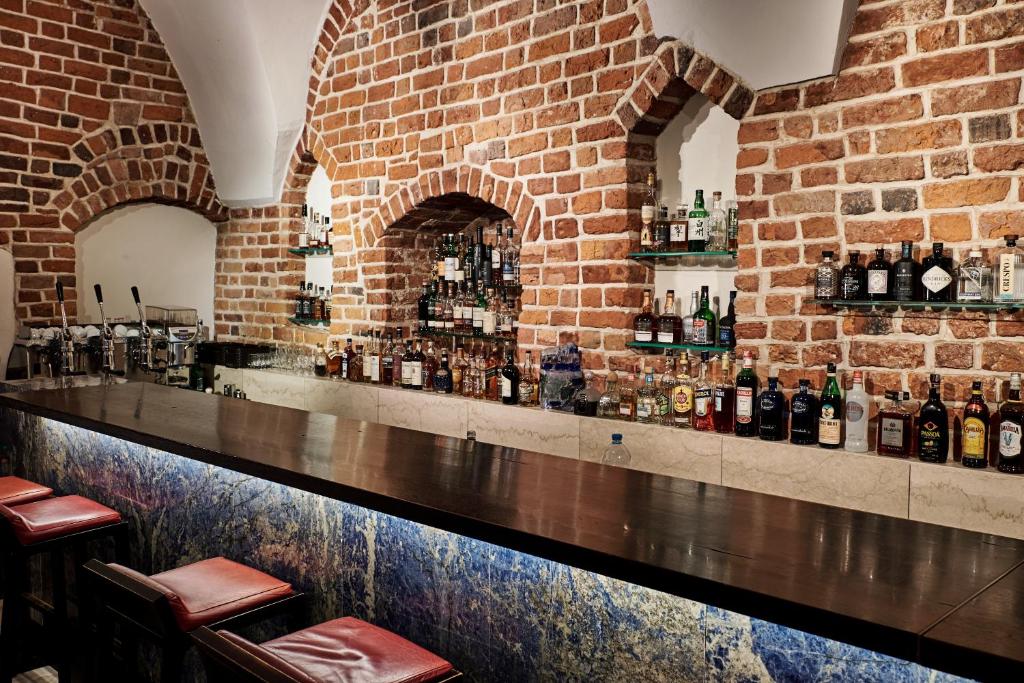 a brick wall with a bar with bottles of alcohol at Hotel Stary in Kraków