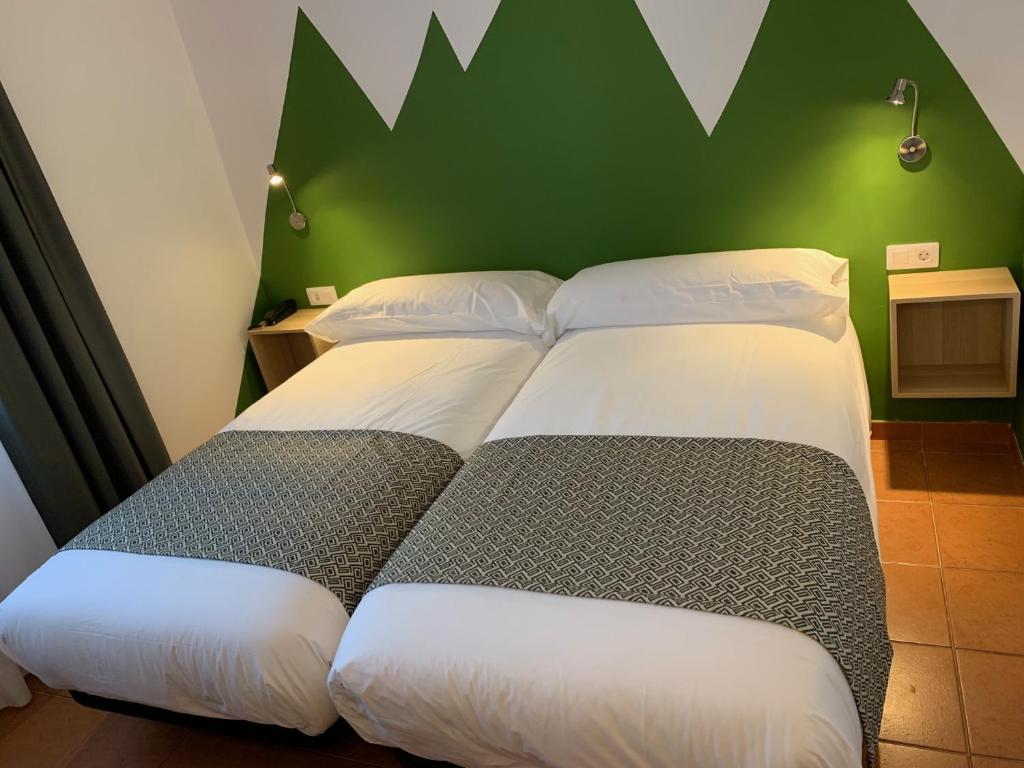 two beds in a room with a green wall at Hotel Musher in Pas de la Casa