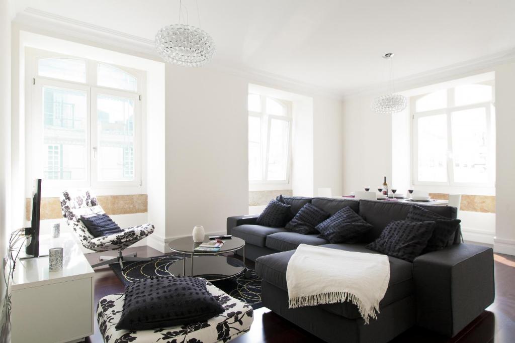 - un salon avec un canapé noir et des chaises dans l'établissement FLH Baixa Elegant Apartment, à Lisbonne