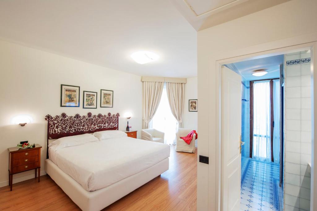 a white bedroom with a bed and a window at Hotel Garden in Siena