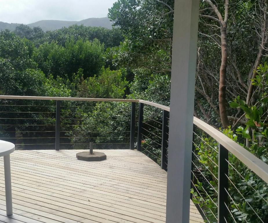 a wooden deck with a view of the forest at Entre Mer et Fôret Beach House Garden Route in Natureʼs Valley