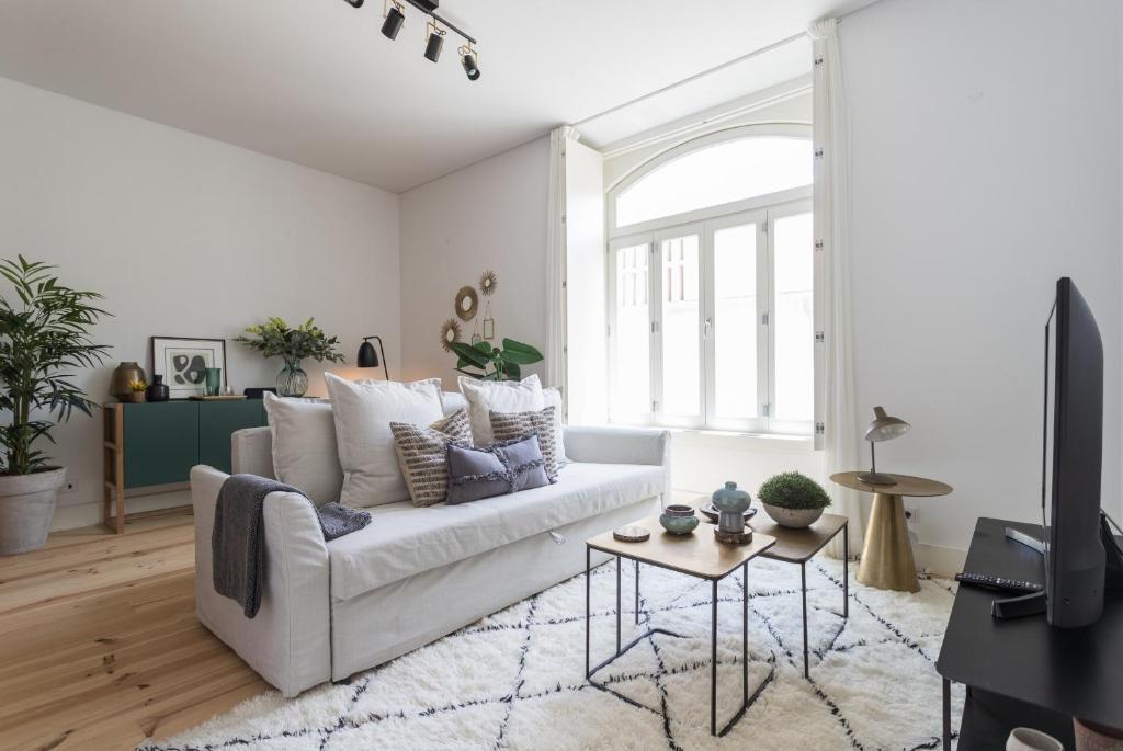 ein Wohnzimmer mit einem weißen Sofa und einem Tisch in der Unterkunft FLH Cais Sodré Charming Flat in Lissabon