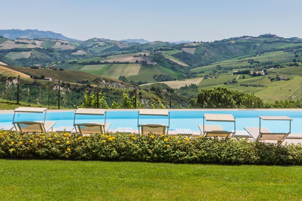 una fila di sedie sedute nell'erba accanto a una piscina di Villa delle Rose a Montalto delle Marche