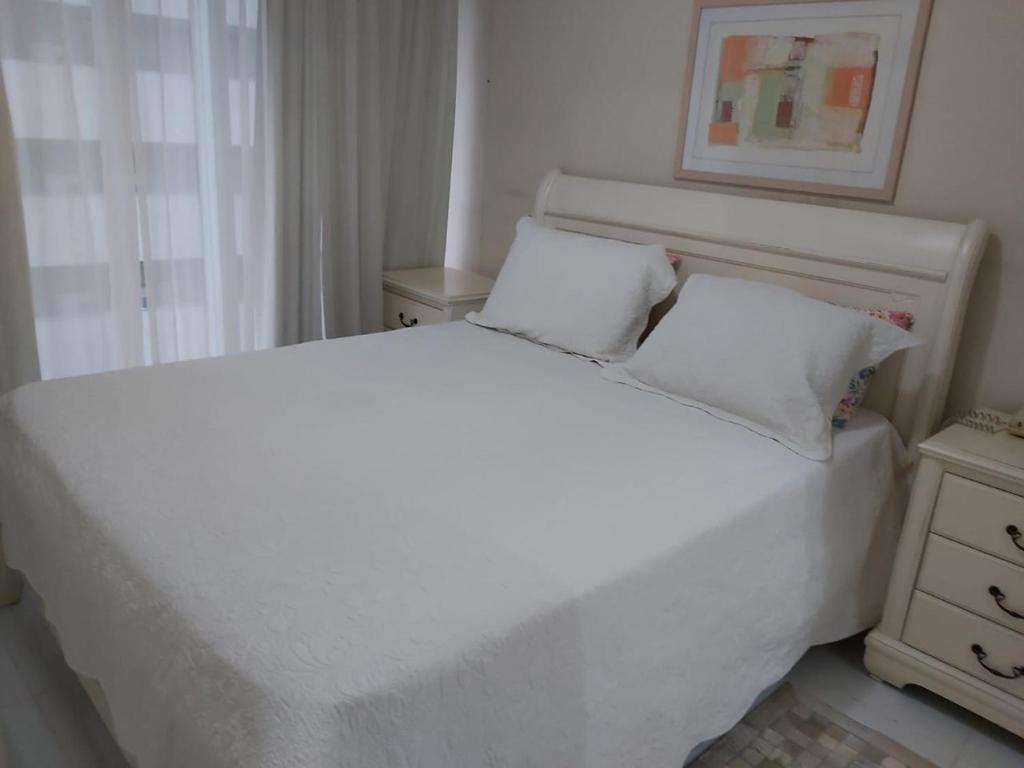 un letto bianco con due cuscini in una camera da letto di Flat Parque Ibirapuera a San Paolo