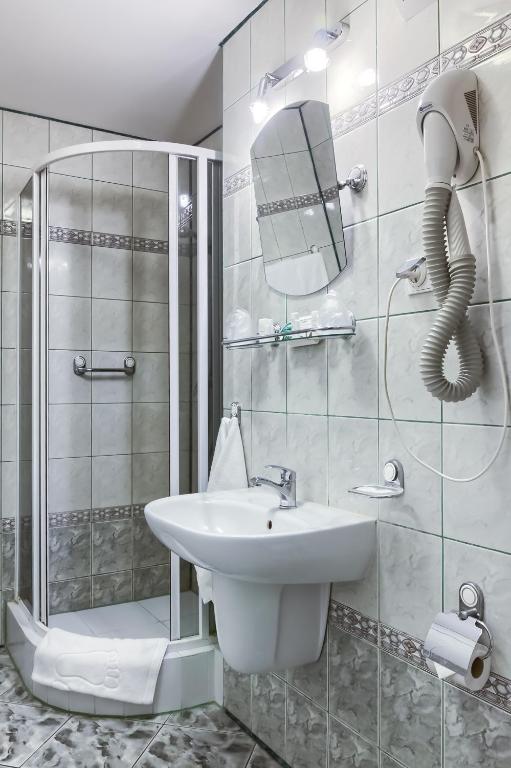 biała łazienka z umywalką i prysznicem w obiekcie Hotel Konin w Koninie