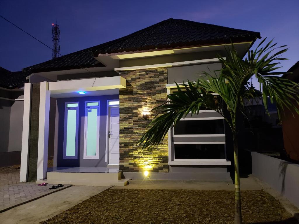 una casa con una puerta azul y una palmera en Brand new vacation house- Private gated community en Banda Aceh
