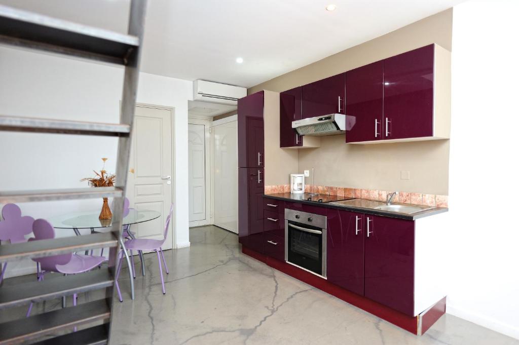 a kitchen with purple cabinets and a table and chairs at Appartement du Tourisme in Zonza
