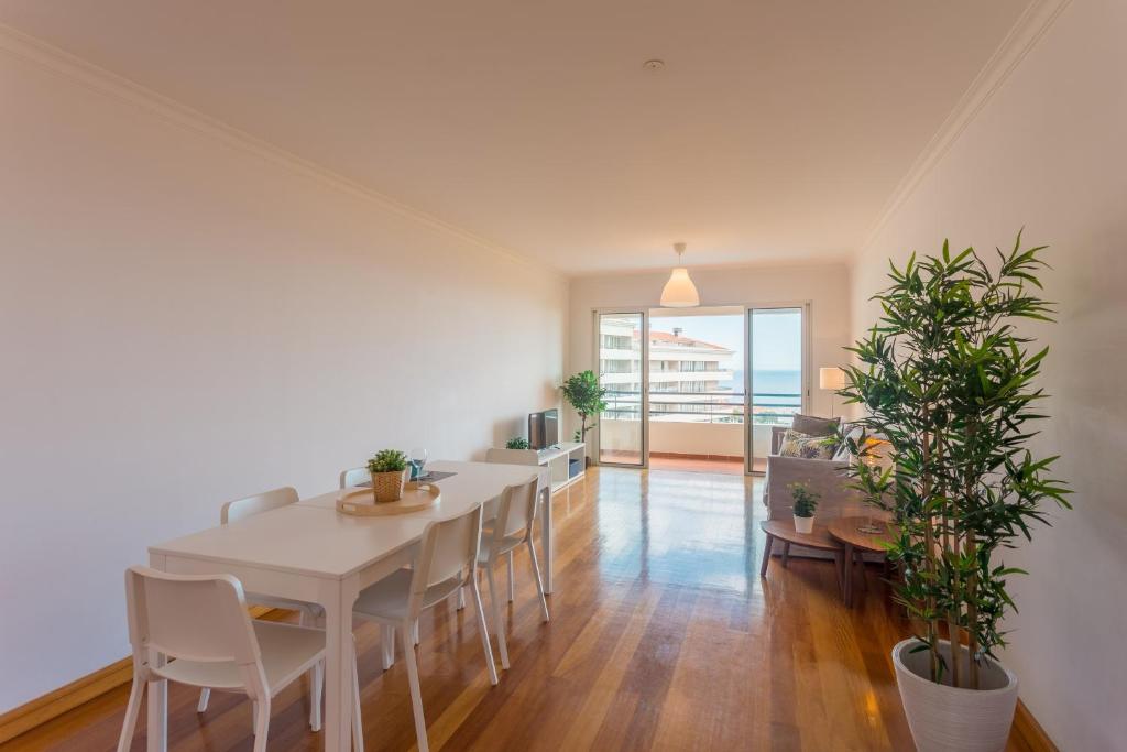 une salle à manger avec une table et des chaises blanches dans l'établissement FLH Funchal Sea View Apartment with Pool, à Funchal