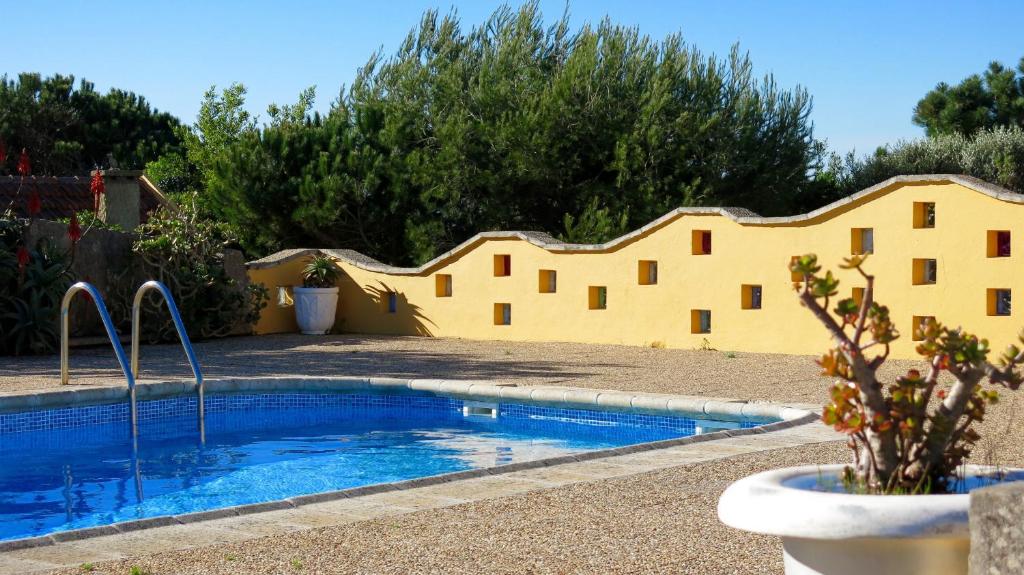 une piscine dans une cour avec un bâtiment jaune dans l'établissement FLH Garden Houses near Ericeira, à Sintra