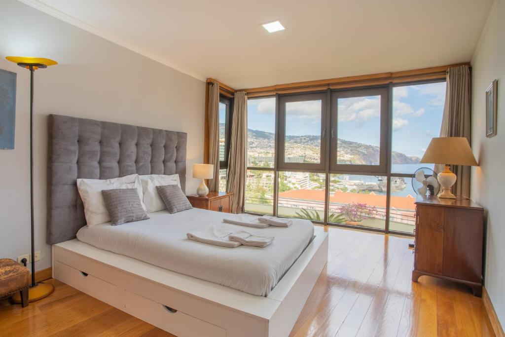 フンシャルにあるFLH Funchal Amazing Sea View Apartment with Poolのベッドルーム1室(大きなベッド1台、大きな窓付)