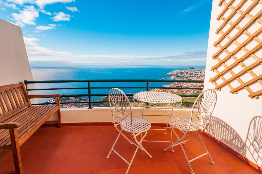 een balkon met tafels en stoelen en uitzicht op de oceaan bij FLH Funchal Ocean View with Pool in Funchal