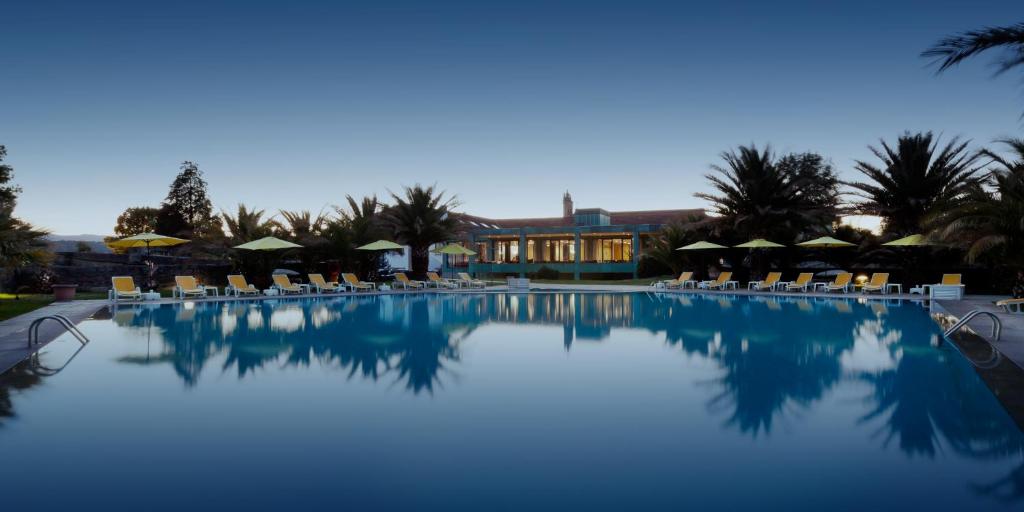 シャヴェスにあるForte de São Francisco Hotel Chavesの椅子とパラソルのある大きなプール