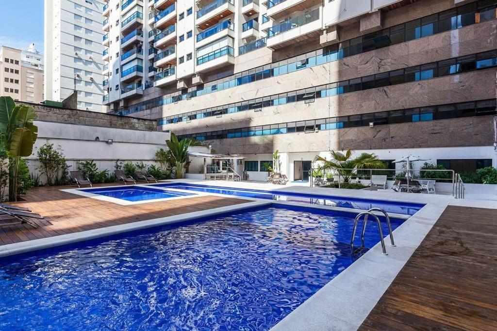 a swimming pool in front of a building at Flats Capitania Varam Pitangueiras in Guarujá