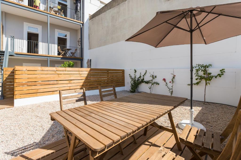 リスボンにあるFLH Intendente Modern Terraceの木製のベンチとパティオ(傘付)