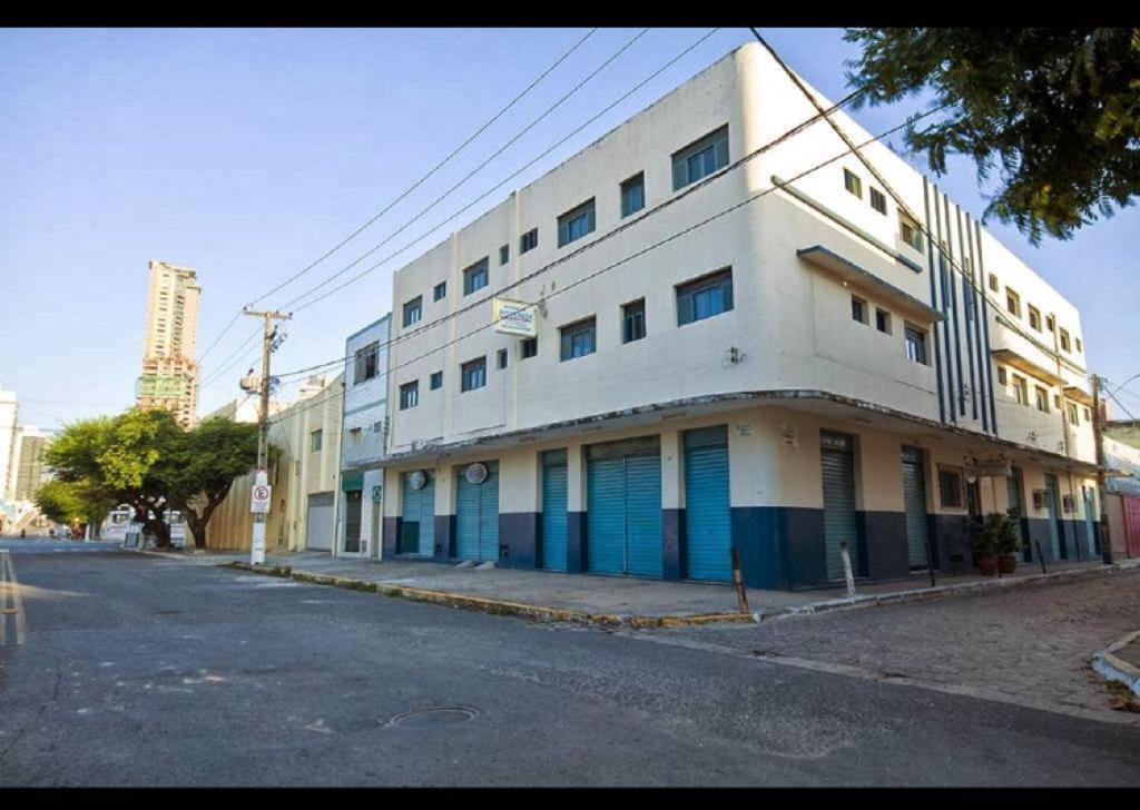 un grand bâtiment blanc avec des portes bleues dans une rue dans l'établissement Residencial Potengy, à Natal