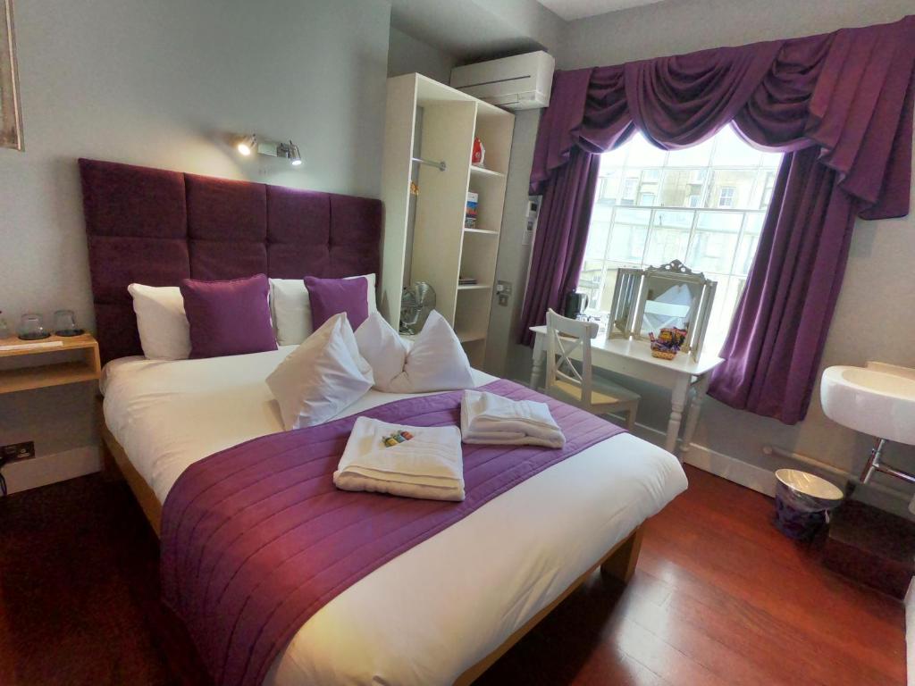 a bedroom with a large bed with two towels on it at The Oriental - Guest House in Brighton & Hove