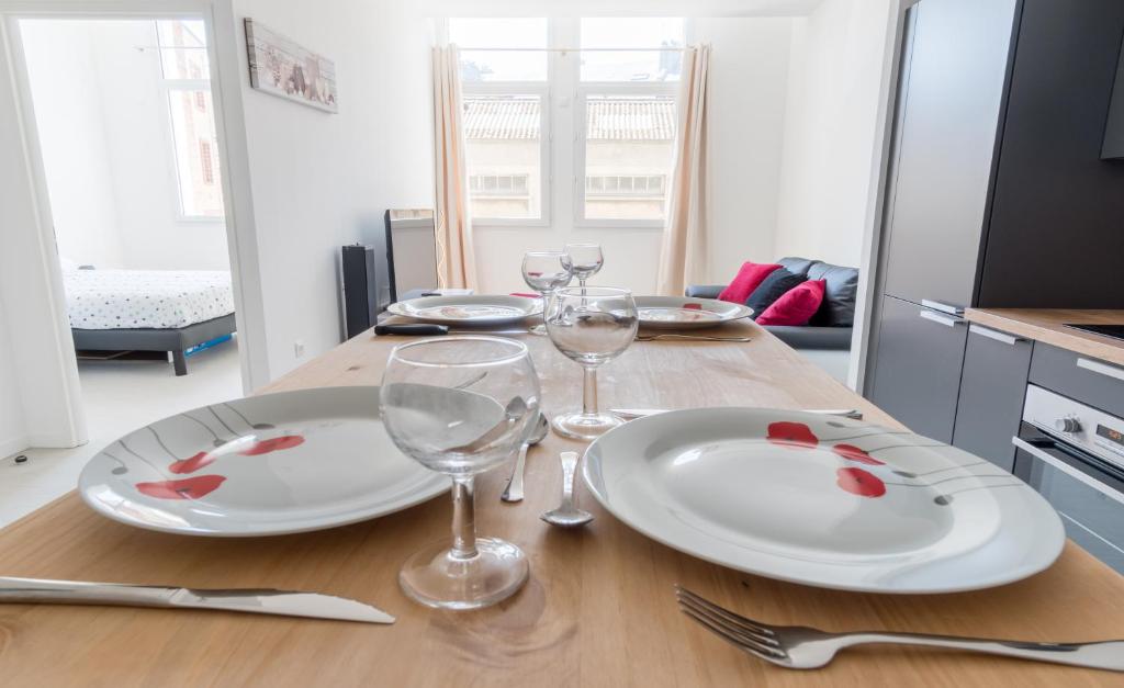 een tafel met twee witte borden en wijnglazen bij Séjour chez le Marin in Le Havre