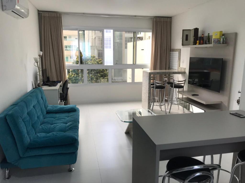 salon z niebieską kanapą i stołem w obiekcie Apartamento 2 dormitórios a 350 metros do mar na Meia Praia - Itapema-sc w mieście Itapema