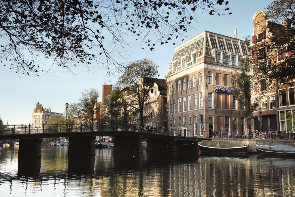 eine Brücke über einen Fluss in einer Stadt mit Gebäuden in der Unterkunft Radisson Blu Hotel, Amsterdam City Center in Amsterdam
