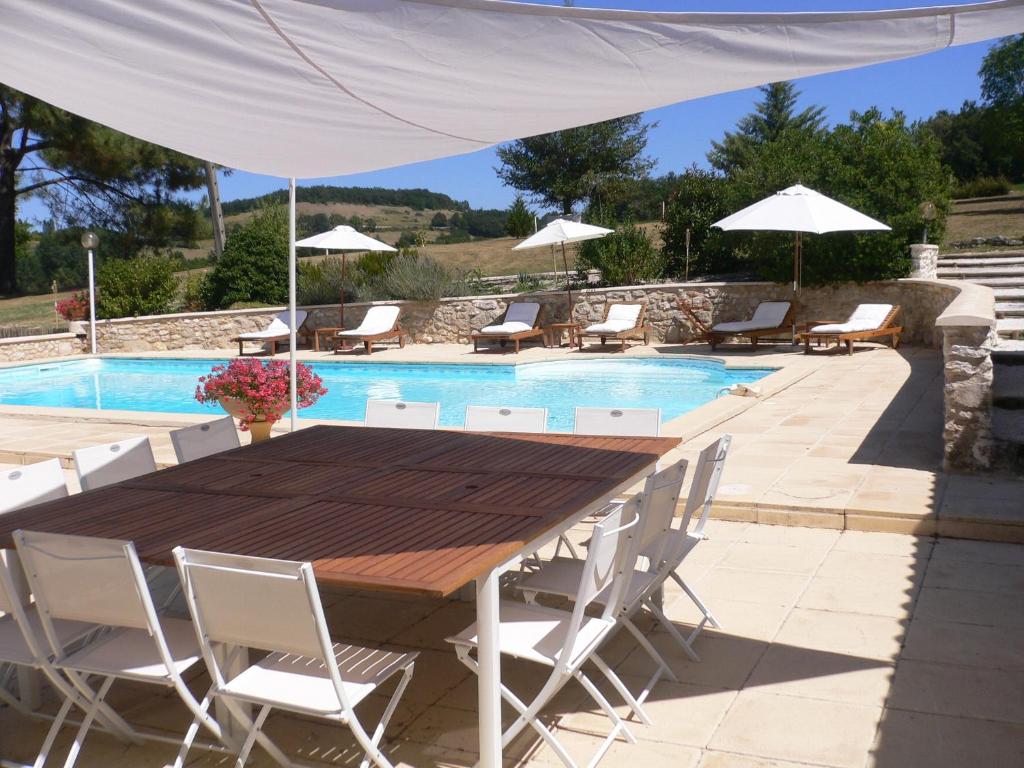 una mesa de madera y sillas junto a una piscina en Chambres d'Hôtes Domaine de Beunes en Pailloles