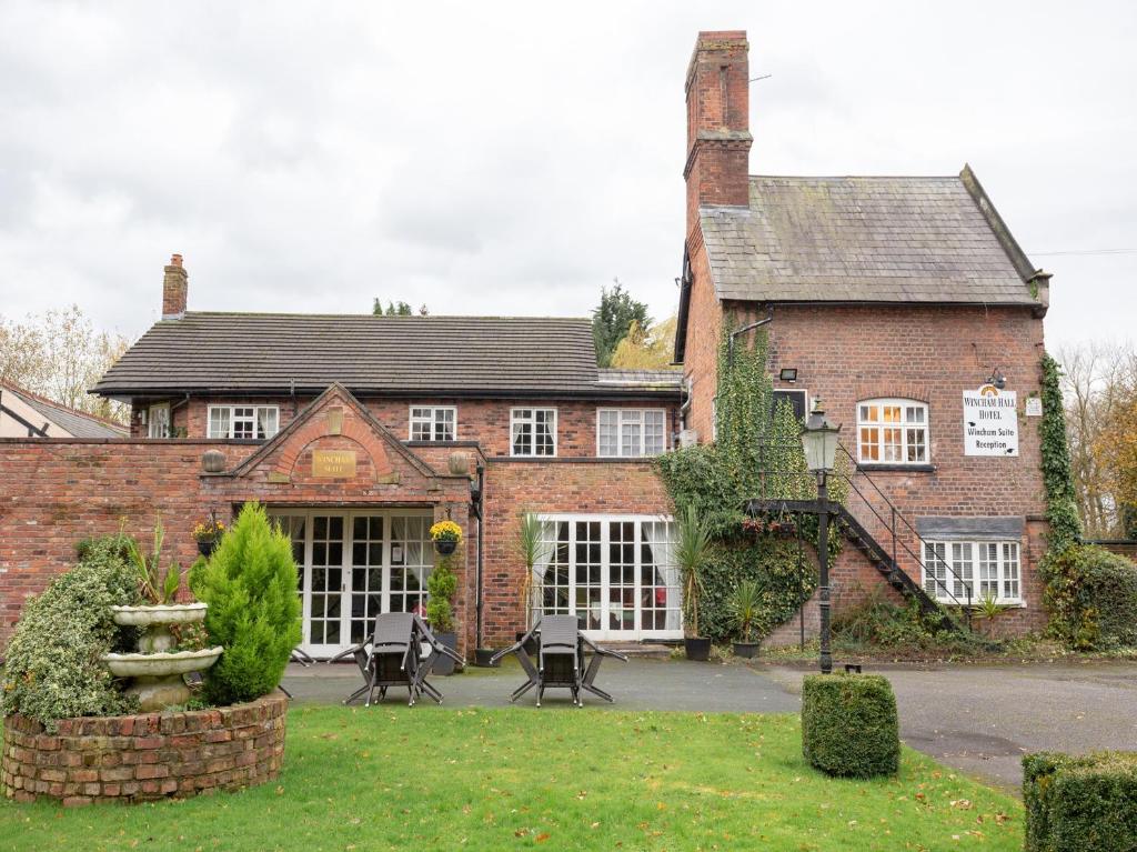 an old brick building with a fountain in front of it at Wincham Hall Hotel in Northwich