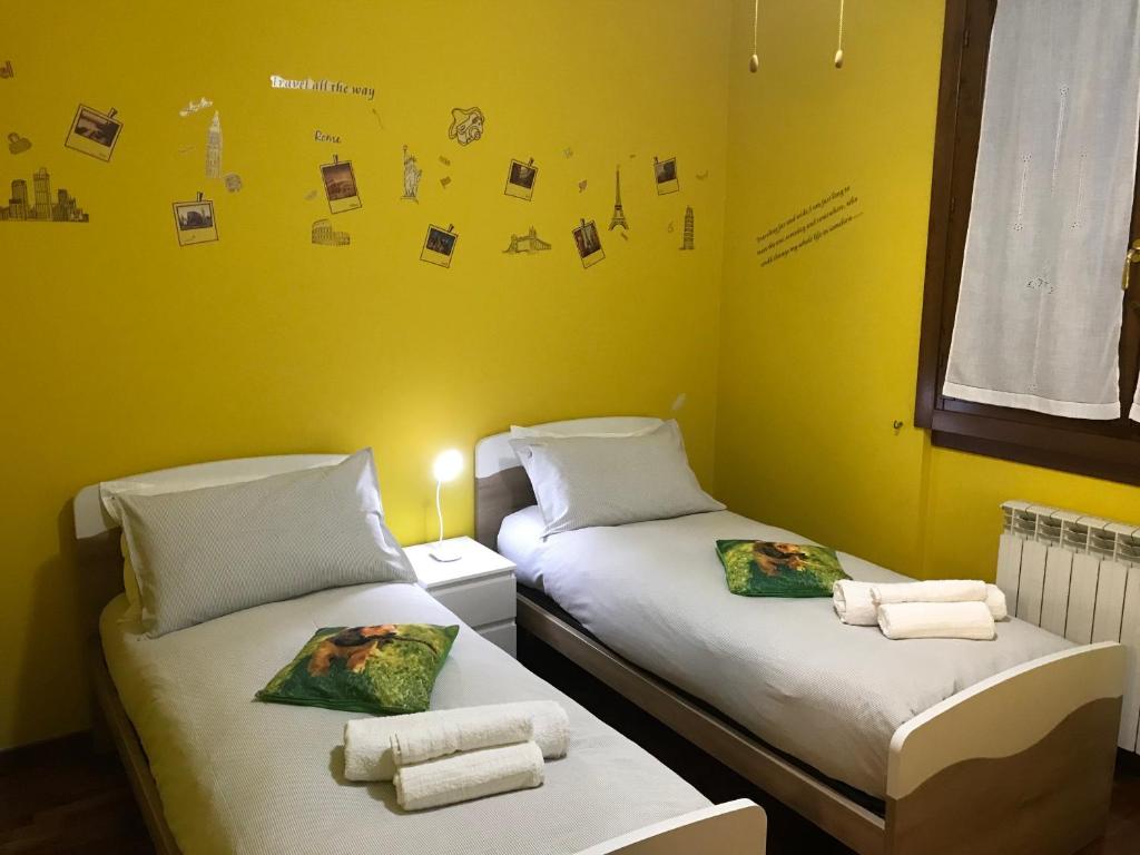 2 łóżka pojedyncze w pokoju z żółtymi ścianami w obiekcie B&B IL VIALETTO w mieście Orio al Serio