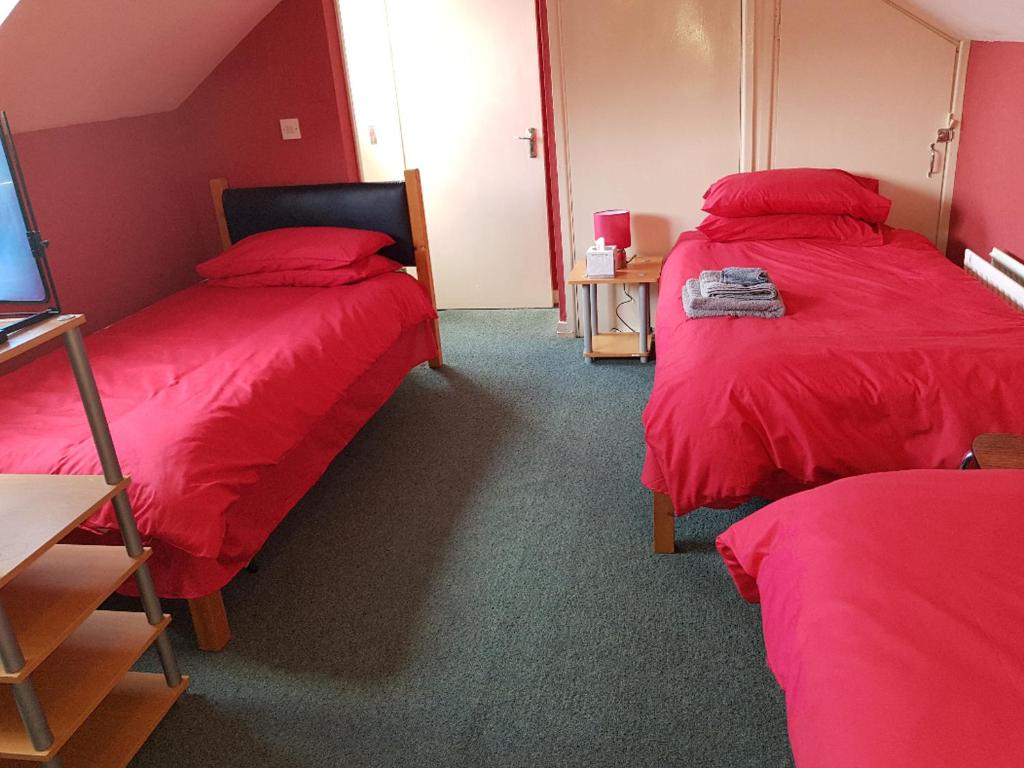 two beds in a room with red sheets at CEAD MILE FAILTE WEST BELFAST in Belfast