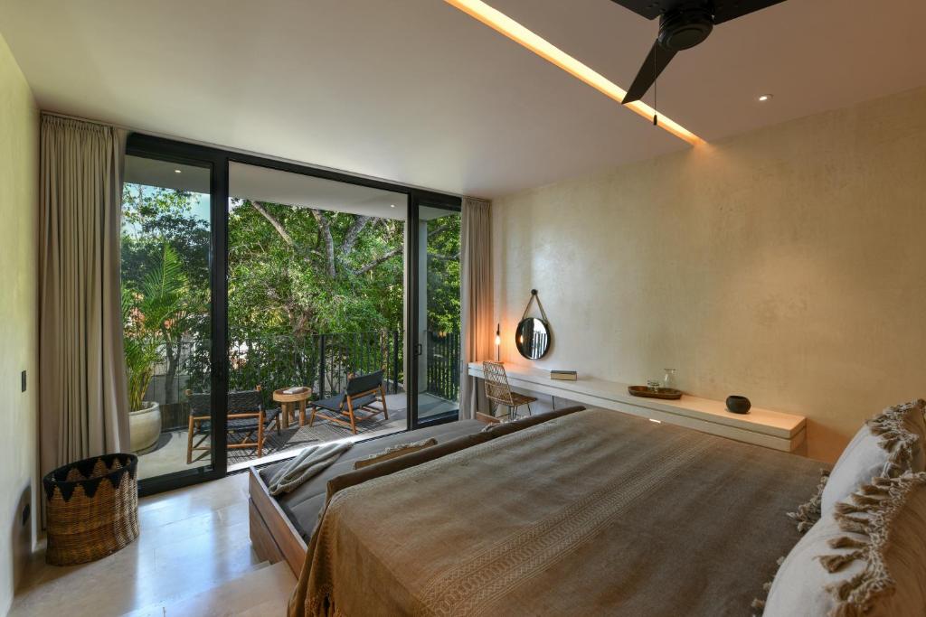 ein Schlafzimmer mit einem großen Bett und einem großen Fenster in der Unterkunft Casa Agape Boutique Hotel Rooftop Pool & Beach club access in Tulum