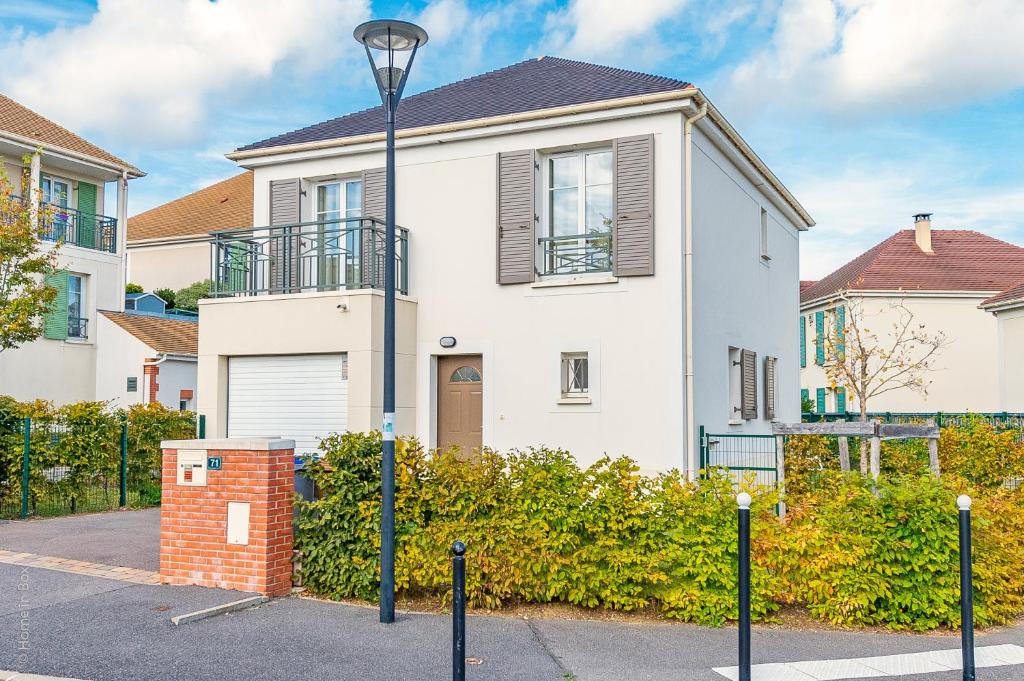 uma casa branca com uma luz de rua em frente em Gîte La Villa Omagny Paris Marne-la-Vallée em Magny-le-Hongre