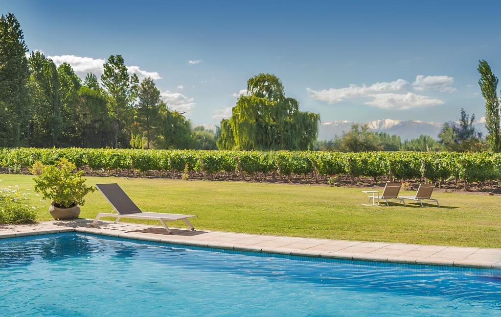 two lounge chairs and a swimming pool in a yard at Postales Hotel Boutique Valle De Uco in Colonia Las Rosas