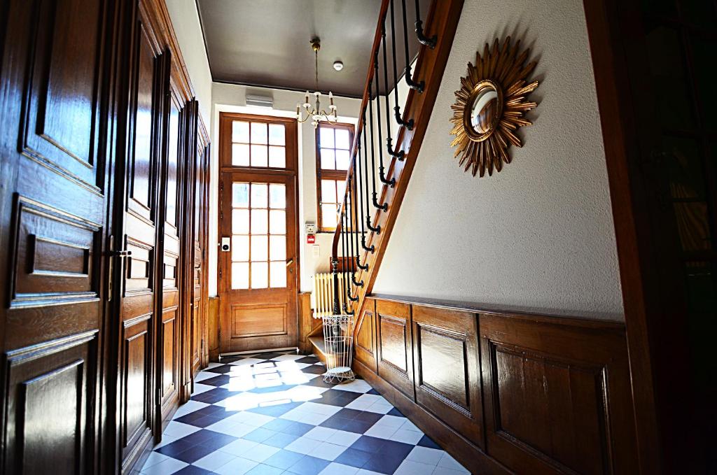 a hallway with a staircase and a checkered floor at La Citadine in Neufchâteau