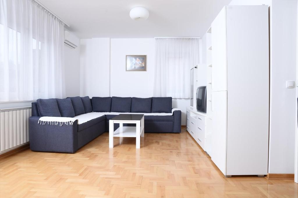 uma sala de estar com um sofá azul e uma mesa em Zap apartman em Belgrado