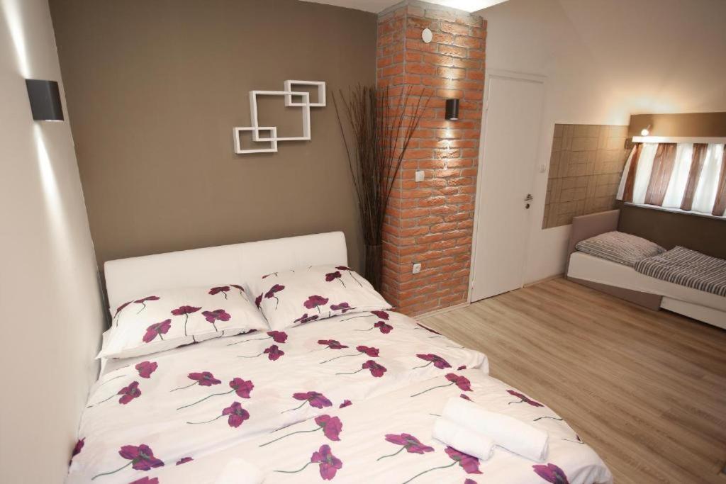 a bedroom with a bed with purple flowers on it at Apartments Rooms PAROMLIN CENTAR in Zagreb