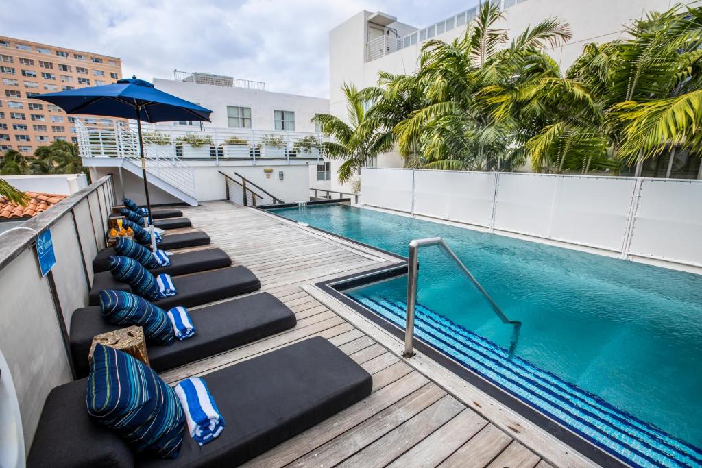 uma piscina no telhado de um edifício com espreguiçadeiras e um guarda-sol em Posh South Beach em Miami Beach