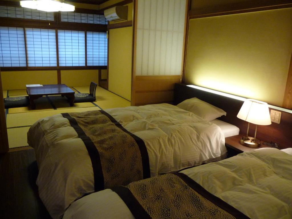 1 dormitorio con 2 camas y mesa con lámpara en Jizokan Matsuya Ryokan, en Nagano