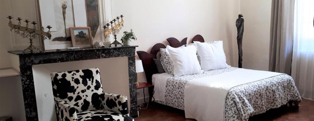- une chambre avec un lit, une cheminée et une chaise dans l'établissement Ô Anges, à Arles