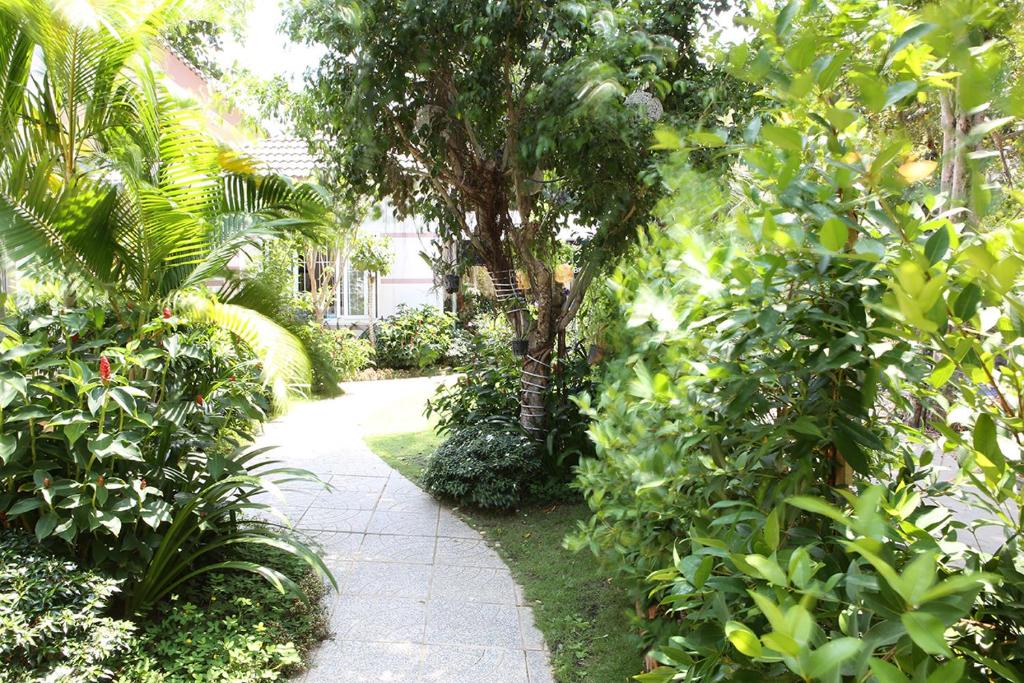 un chemin à travers un jardin planté d'arbres et de plantes dans l'établissement Huynh Gia Bungalow, à Duong Dong