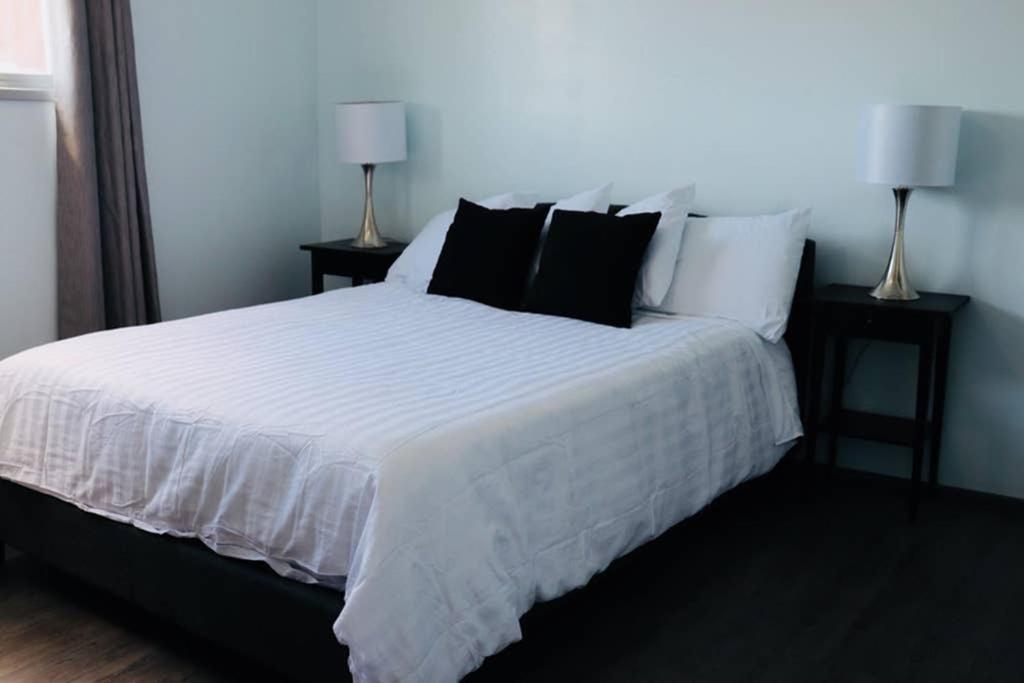 a bedroom with a white bed with black pillows at Sun Dog Manor in Maple Creek