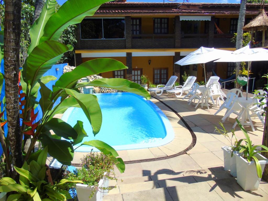 a swimming pool in the middle of a patio with chairs and umbrellas at Pousada A Flor da Terra in Arraial d'Ajuda
