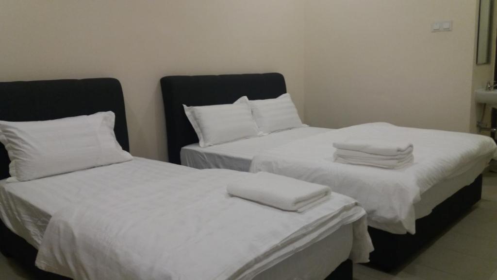 GLG KLIA Transit House في سيبانغ: سريرين في غرفة ذات أغطية ووسائد بيضاء
