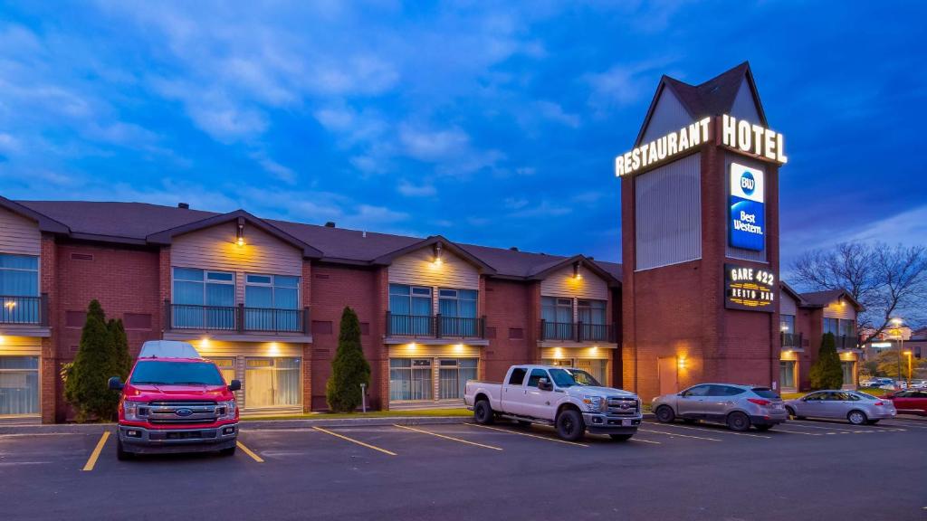 a hotel with cars parked in a parking lot at Best Western Hotel St. Jerome in Saint-Jérôme
