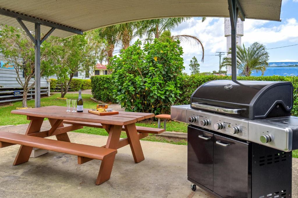 a picnic table with a grill and a picnic table with a picnic at Tin Can Bay's Sleepy Lagoon Motel in Tin Can Bay