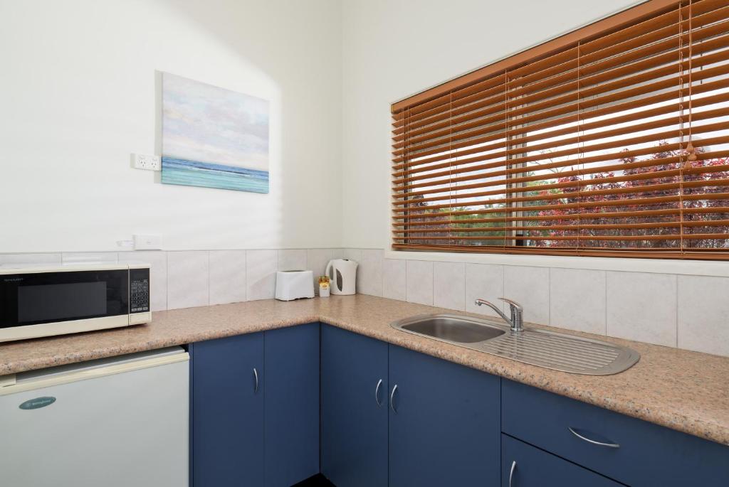 a kitchen with a sink and a microwave at Tin Can Bay's Sleepy Lagoon Motel in Tin Can Bay