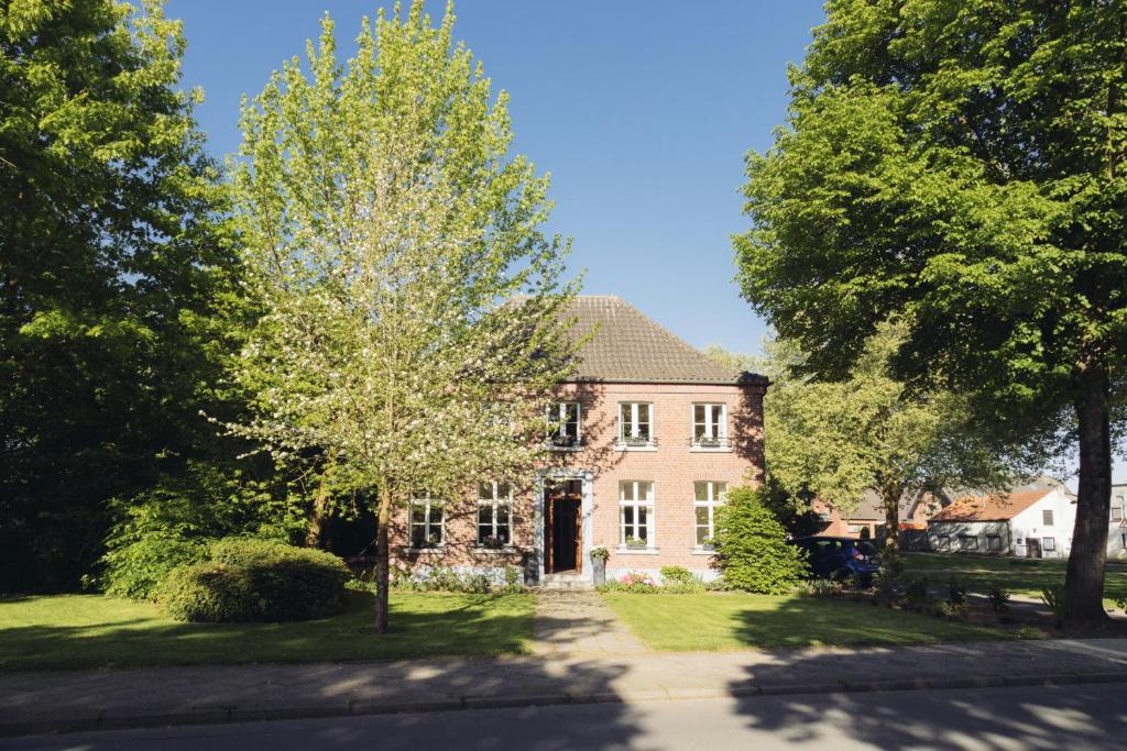 een groot bakstenen huis met bomen ervoor bij Altes Pfarrhaus in Geldern