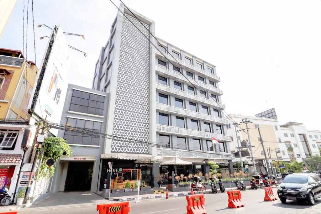 een hoog gebouw in een stadsstraat met verkeerskegels bij Unisi Hotel Malioboro - Jogja Syariah in Yogyakarta