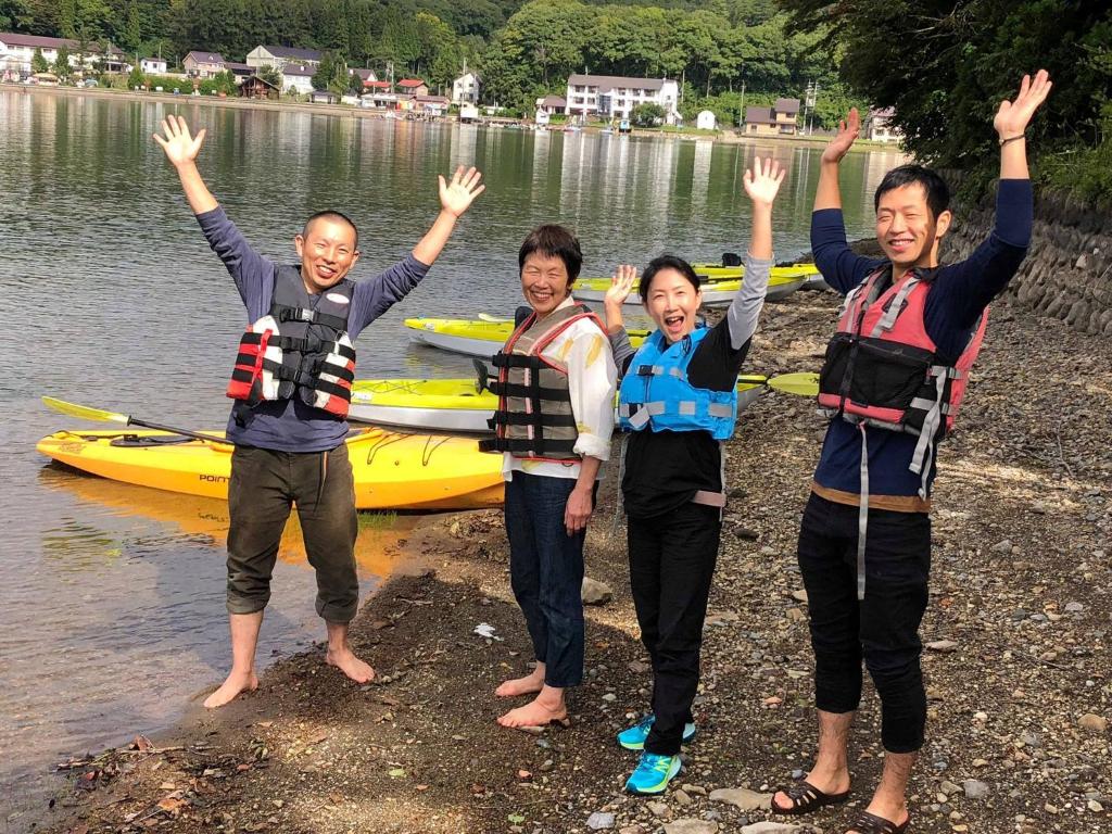 a group of people standing on the shore of a lake at Nojiri Lake Resort in Shinano