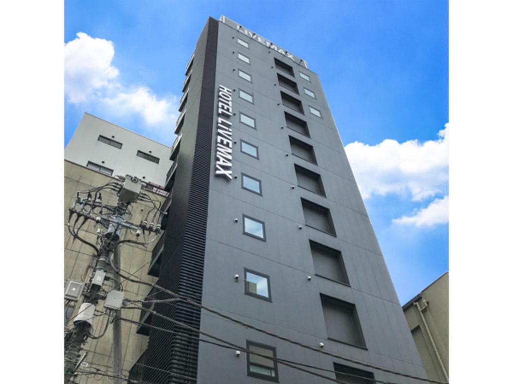 wysoki szary budynek z napisem w obiekcie HOTEL LiVEMAX Tokyo Kanda-Ekimae w Tokio