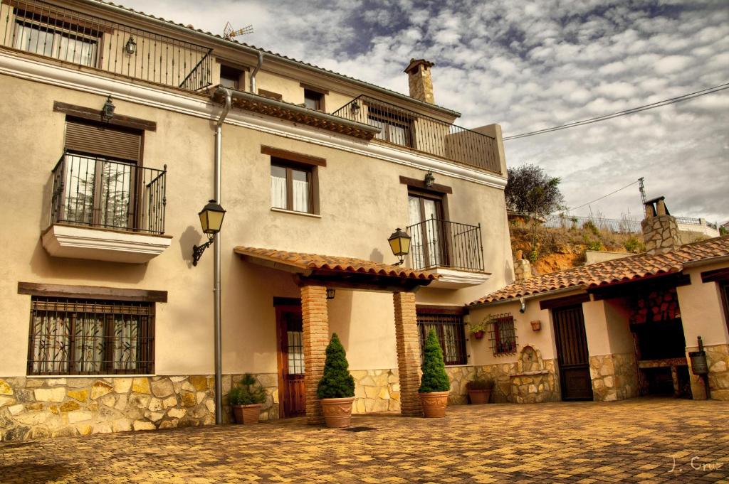 a large white building with a cobblestone street at Alojamientos Rurales la Fuente in Villalba de la Sierra