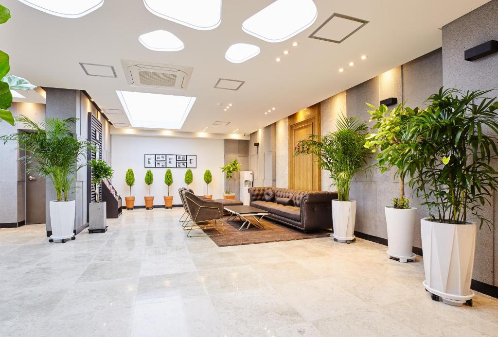 a lobby with a couch and potted plants at Noble Stay Hotel in Gwangju